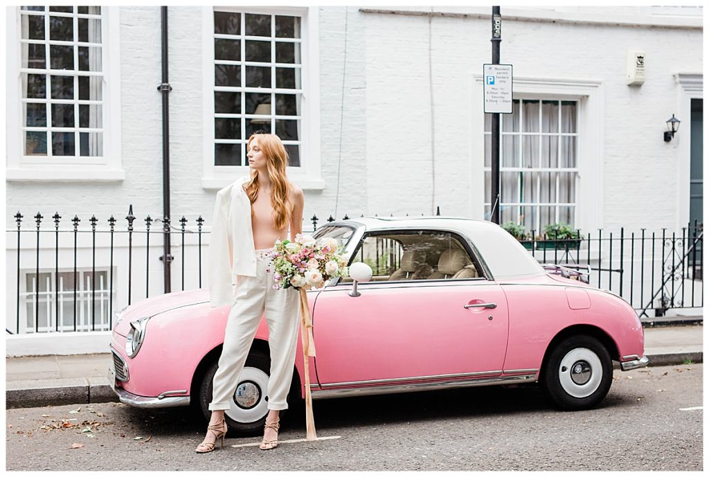 woman with bouquet in front of pink car